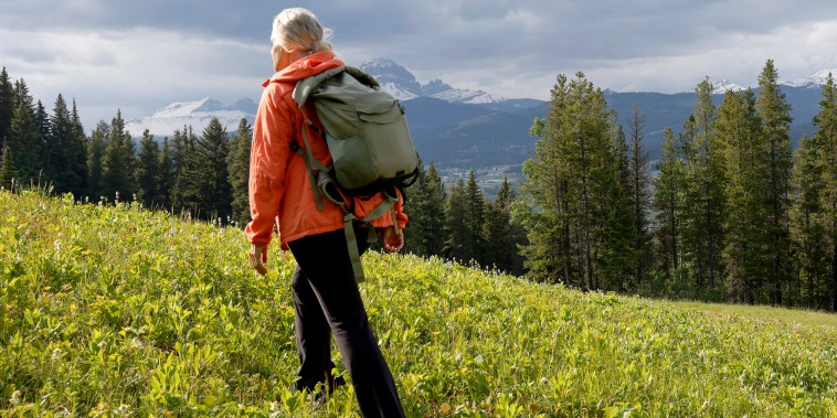 Image: Mature woman hiking through a mountain meadow