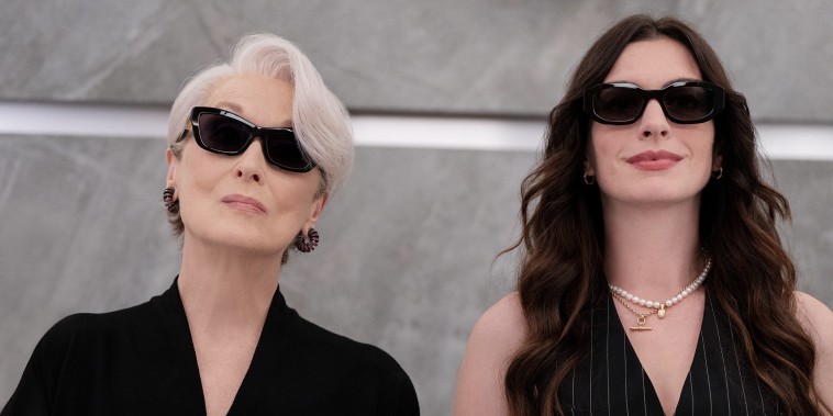 Meryl Streep and Anne Hathaway stand side by side wearing dark sunglasses.