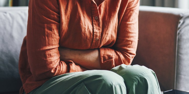 Woman Experiencing Pain While Sitting on a Couch at Home