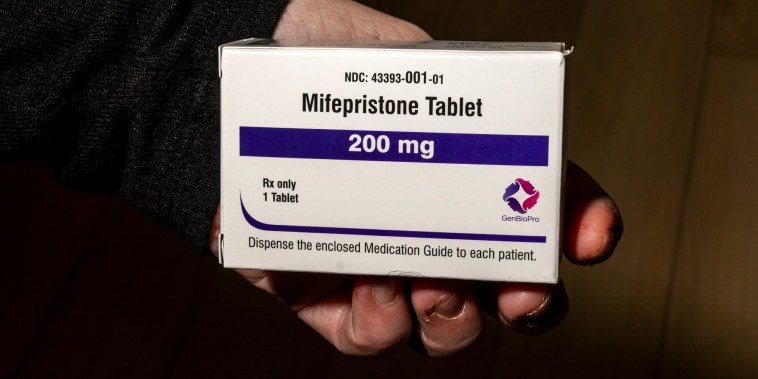 A hand holds a box of mifepristone