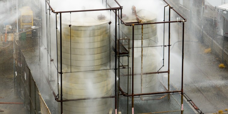 Steam and mist rising off of industrial tanks.