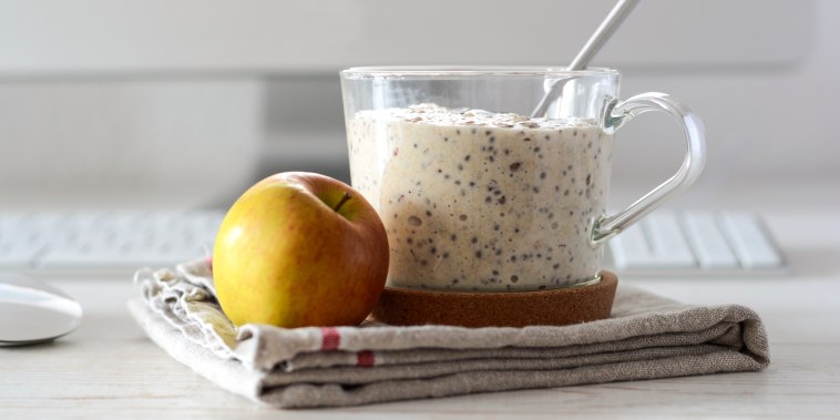 Glass of porridge with linseed and chia seed and an apple on desk
