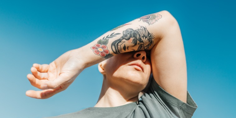 Woman covering her eyes with her arm with tattoo