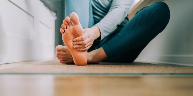 Woman massages her feet on yoga mat