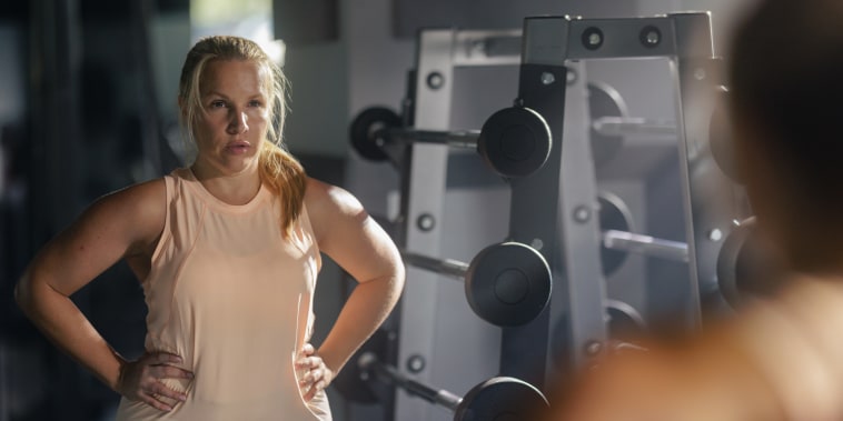 Woman looks at reflection in gym mirror