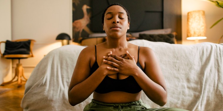 Woman meditating on exercise mat in bedroom at home