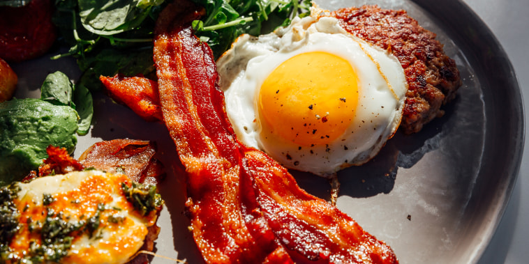 Keto breakfast with fried egg, bacon, cheese, ground beef and salad