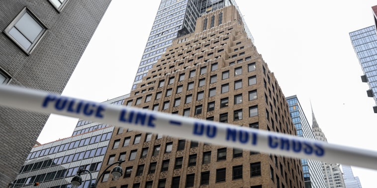 White tape with blue lettering reading POLICE LINE - DO NOT CROSS stretched in front of high-rise buildings in downtown Manhattan.
