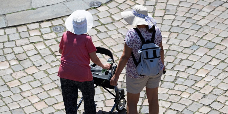 Women walking on a stone street Dresden's Old Town wearing sun hats. One woman has a walker.
