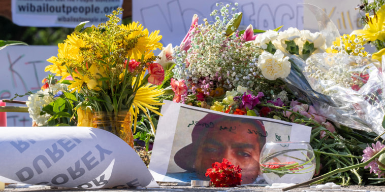 A picture of Corey Ruiz is on the ground surrounded by posters and flowers