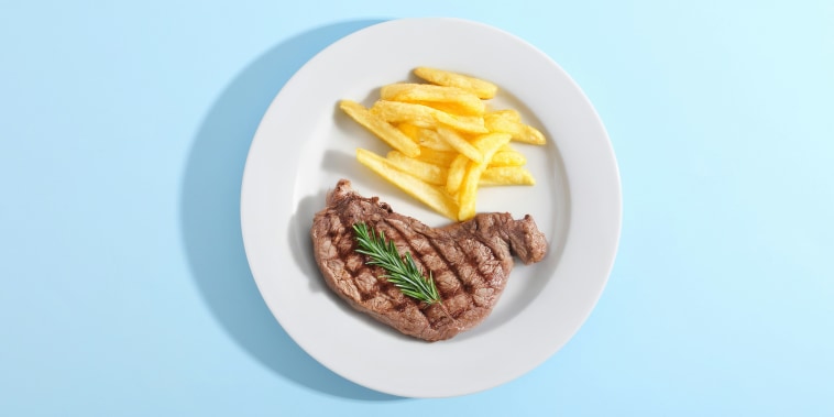 Grilled Steak with French Fries and Rosemary on a White Plate, Top View on Blue Background