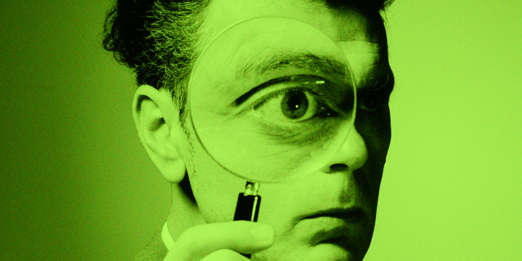 A man holding a magnifying glass to his eye.