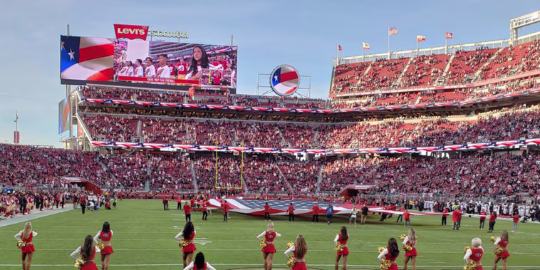 Image: A San Francisco 49ers cheerleader kneels during the national anthem