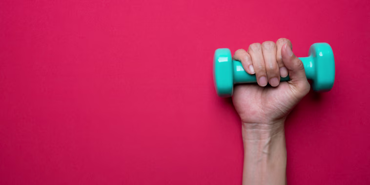 A woman holds a dumbbell