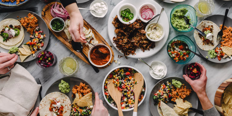 Cropped hands of friends having food at table during social gathering