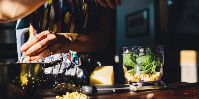 Woman preparing pasta with basil, pine nuts