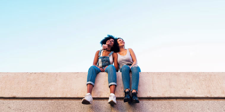 Image: Female Friends Taking Selfie While Sitting On Wall