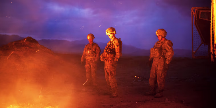 Soldiers burn trash in a burn pit
