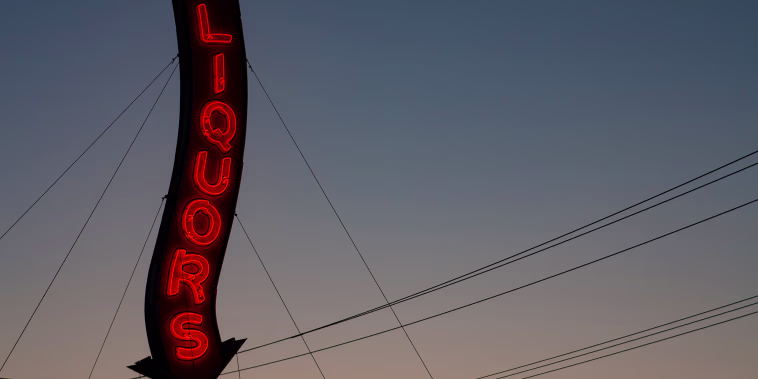 An old-fashioned, red, neon sign that reads "Liquors."