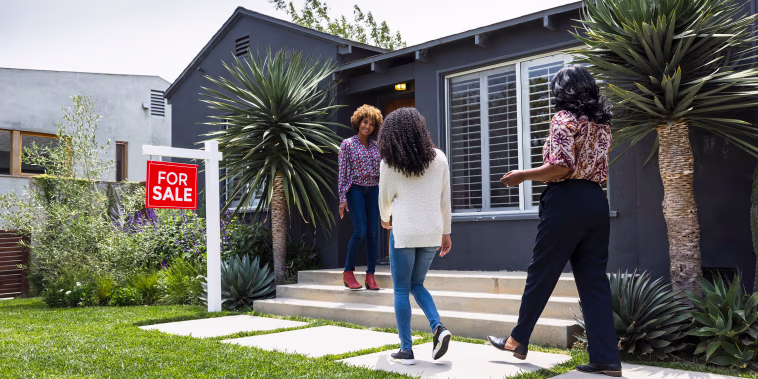 Full length of saleswoman greeting female customers while standing outside house