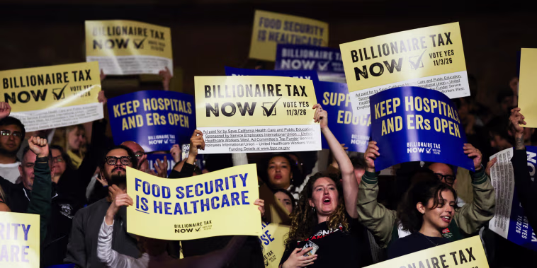 People hold posters in favor of the billionaire tax act