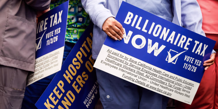 People hold signs calling for a billionaire tax