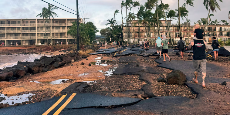 People walk past a damaged road