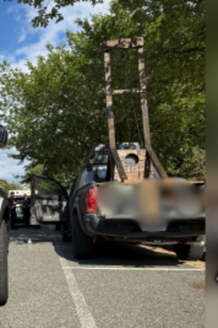 The United States Capitol Police car is seen next to a guillotine in a parking lot.