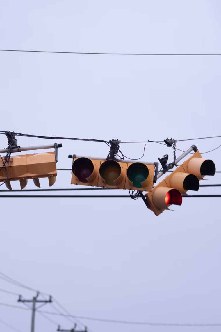 Tangled stoplights hang against a gray sky.