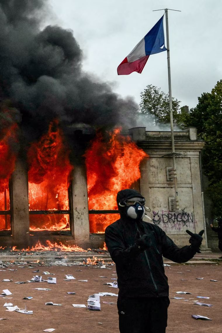 Protesters stand in front of Lyon's tourism office set on fire.