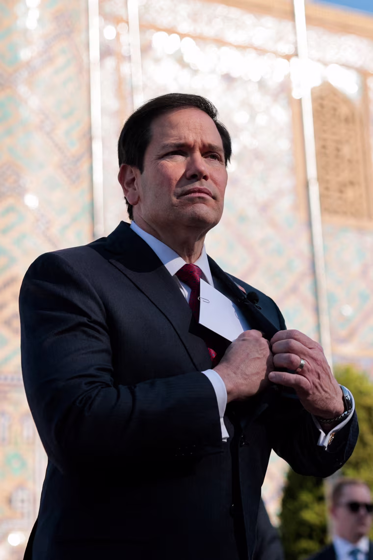 Image: Marco Rubio putting a piece of paper into the inner pocket of his jacket, as he walks through Registan Square in Samarkand.
