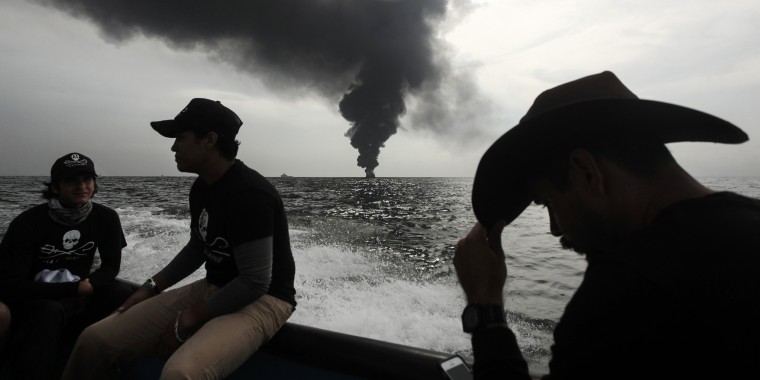 Image: Members of the marine wildlife conservation organization Sea Shepherd monitor the fuel tanker Burgos as it burns