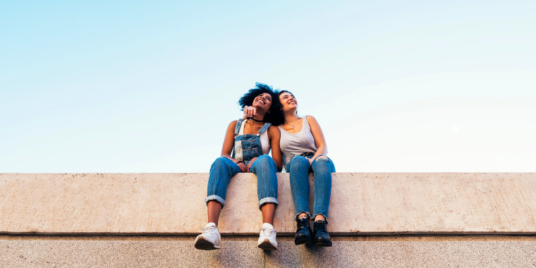 Image: Female Friends Taking Selfie While Sitting On Wall
