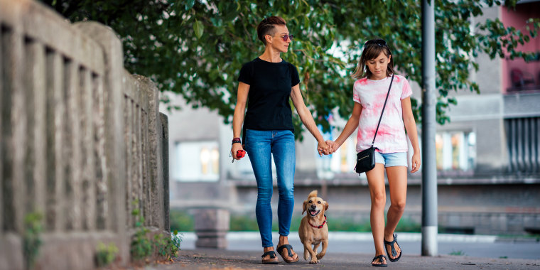 Mother and daughter walking on the street with a dog
