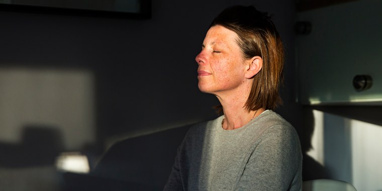 Woman closing her eyes as the last sun rays of the day come into her house