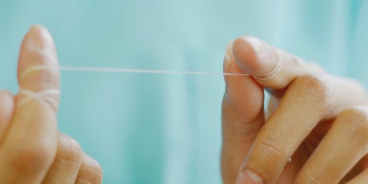 Close up of woman's hands with dental floss