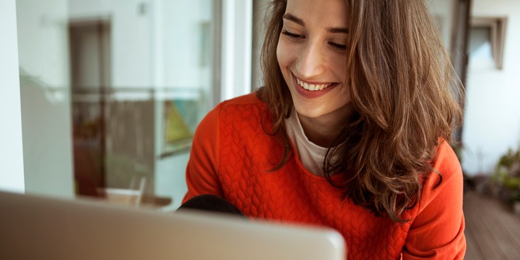 Smiling young woman using laptop on balcony