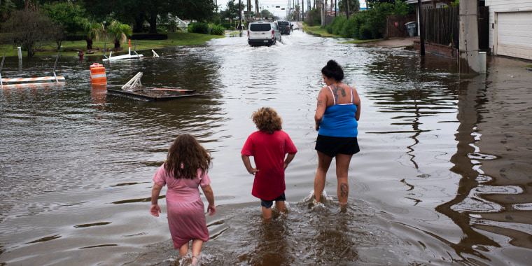 A mother and her children through flood waters after Hurricane Nicholas landed in Galveston, Texas, on Sept. 14, 2021.