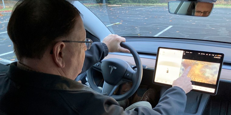 Vince Patton, a new Tesla owner, demonstrates on a closed course in Portland, Ore., how he can play video games on the vehicle's console while driving on Dec. 8, 2021.