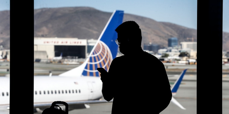 A traveler checks his mobile phone while waiting to board a flight to Honolulu at SFO in San Francisco on Oct. 15, 2020.