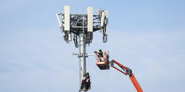 Workers install equipment on a 5G cell tower in Salt Lake City on Jan. 11, 2022.