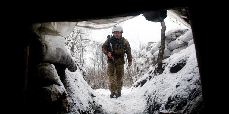 A Ukrainian Military Forces serviceman walks along a snow covered trench on the frontline with the Russia-backed separatists near Zolote village, in the eastern Lugansk region, on Jan. 21, 2022.