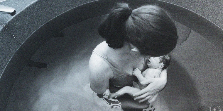 Image: Woman holds her baby in a pool after natural water birth.