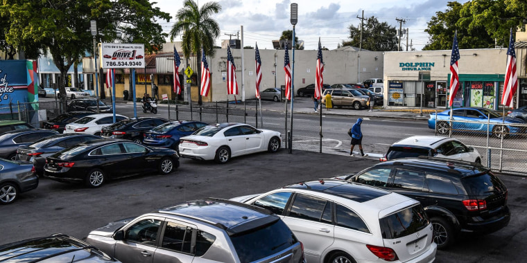 Image: A pedestrian walks past a pre-owned car sales lot in Miami on Jan. 12, 2022.