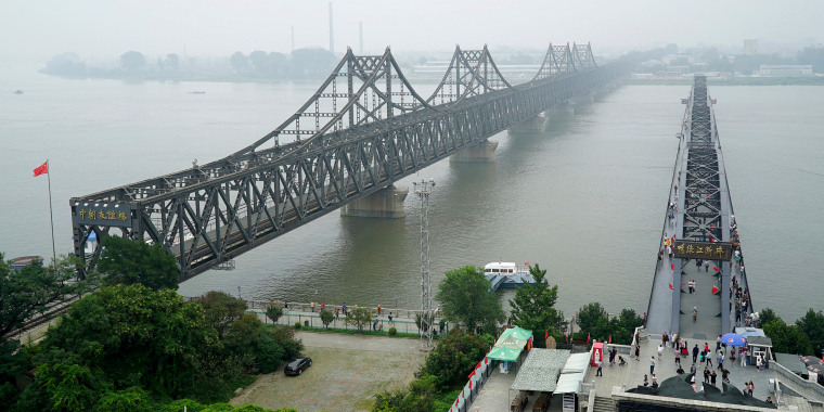Visitors walk across the Yalu River Broken Bridge, right, next to the Friendship Bridge connecting China and North Korea in Dandong in northeastern China's Liaoning province, on Sept. 9, 2017.