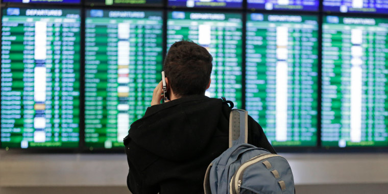 Un viajero habla por teléfono mientras observa el tablero de llegadas y salidas en el Aeropuerto Internacional de San Francisco.