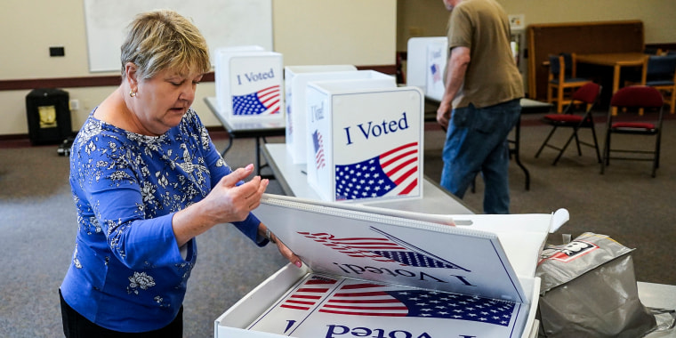 Image: Cecelia Peterson, the majority inspector for the Cranberry West 5 voting precinct, left, and clerk Fred Peterson set up some of the folding voting booth dividers that will be used for voting in Tuesday's Pennsylvania Primary Election, on May 16, 2022, in Cranberry Township, Pa.