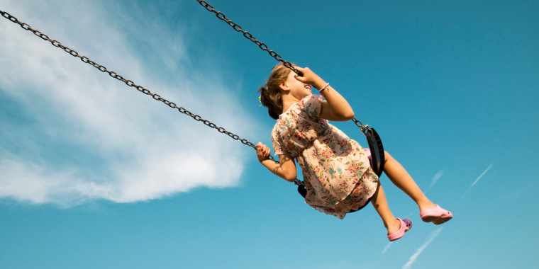 Little Girl Swinging Against Blue Sky