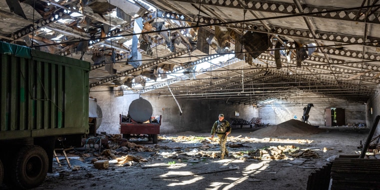 A Ukrainian army officer inspects a grain warehouse on May 6, 2022, that was shelled by Russian forces near the frontlines of Kherson Oblast in Novovorontsovka.