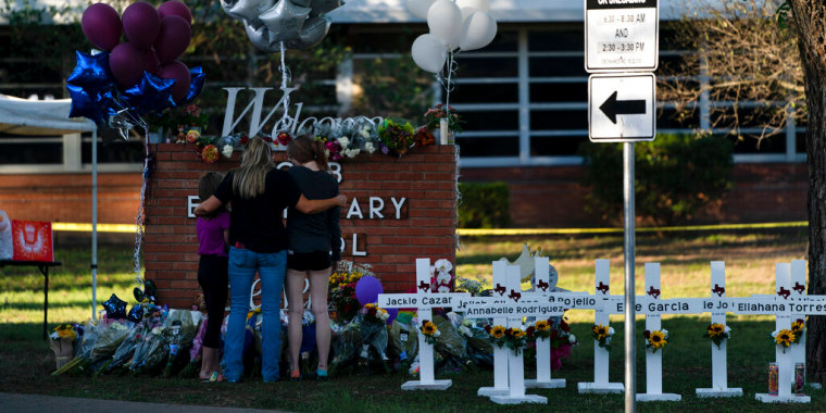 Una familia presenta sus respetos junto a las cruces con los nombres de las víctimas del tiroteo del martes en la escuela primaria Robb en Uvalde, Texas, el jueves 26 de mayo de 2022.